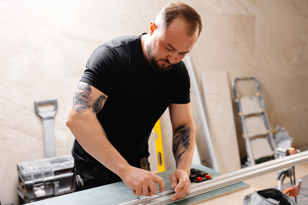 Construction worker cutting aluminum profiles for installing stretch ceiling